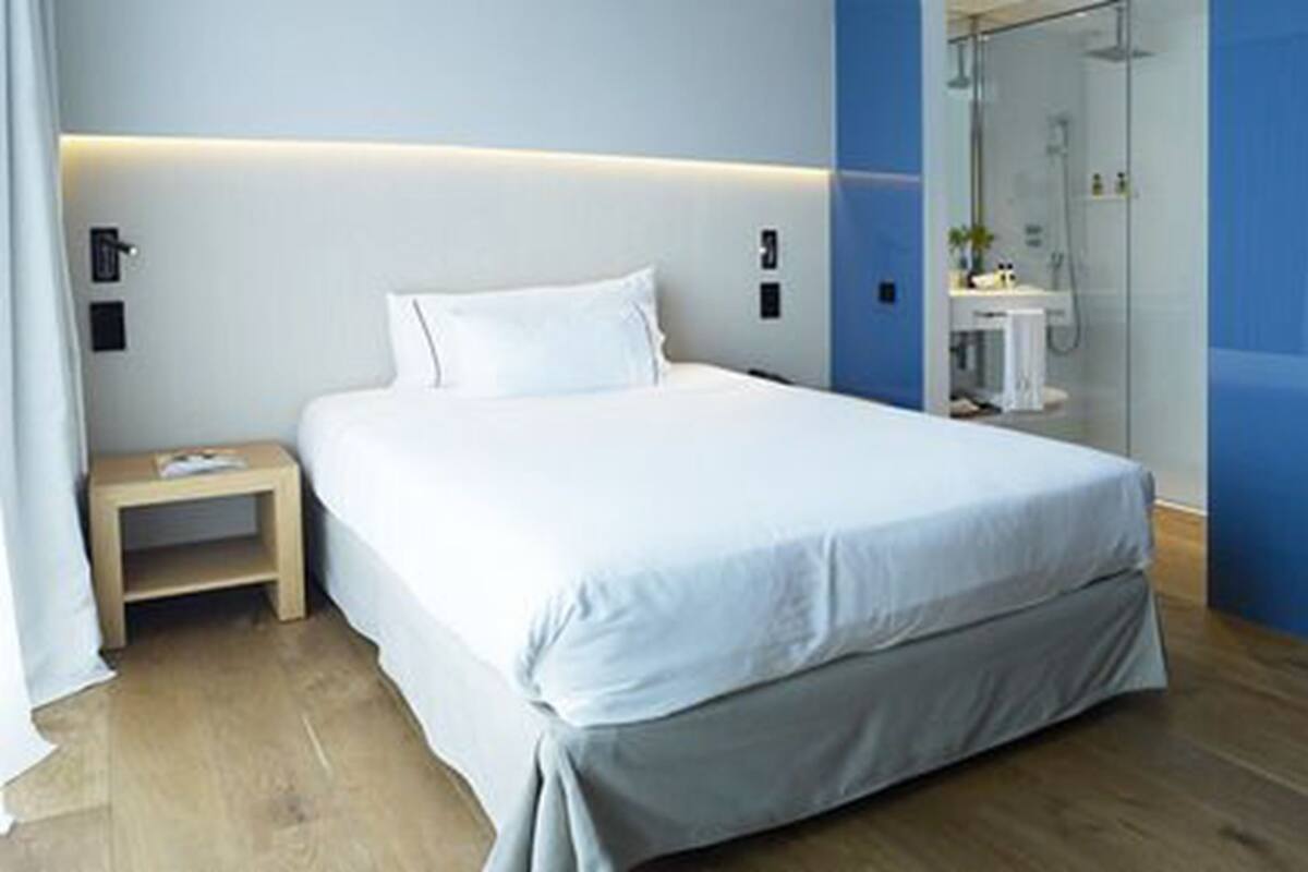 A modern bedroom with a large bed, a bedside table, and a glass shower area.