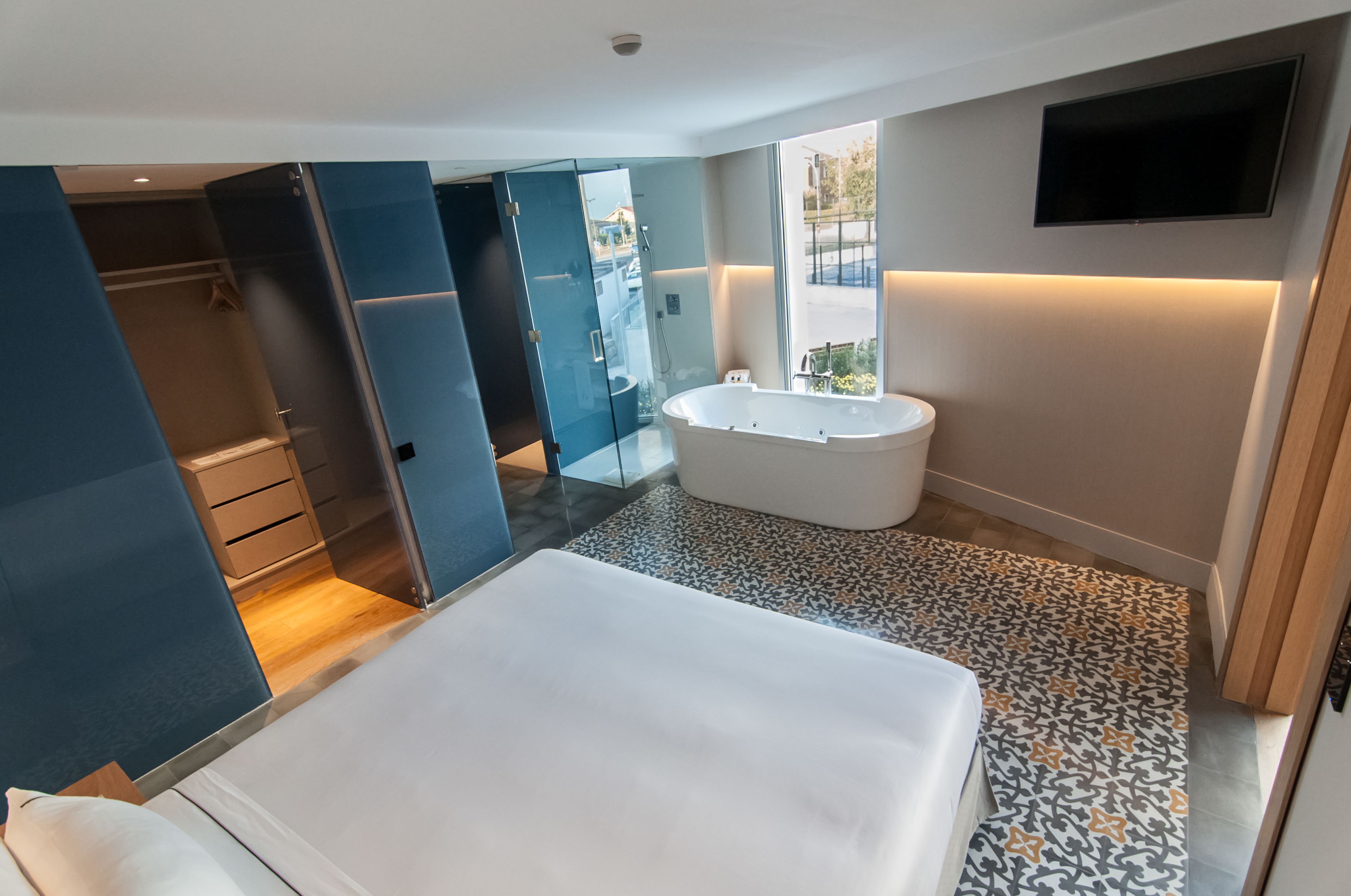 Une salle de bain moderne dotée d’une grande baignoire, d’une douche à l’italienne et d’un dressing ouvert avec des parois en verre.