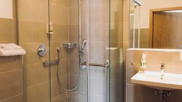 A modern bathroom with a glass-enclosed shower, a toilet, and a sink with a mirror.