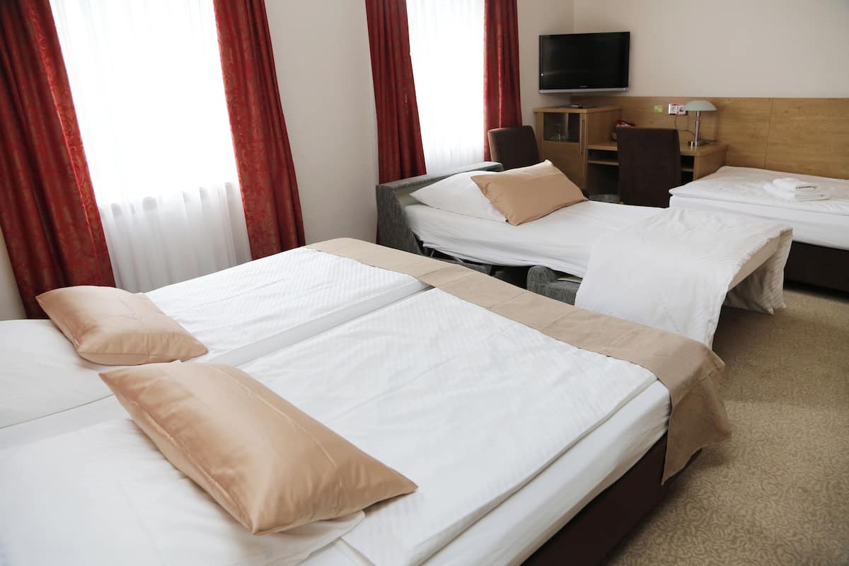 Een hotelkamer met twee enkele bedden, een televisie, een bureau en een stoel.