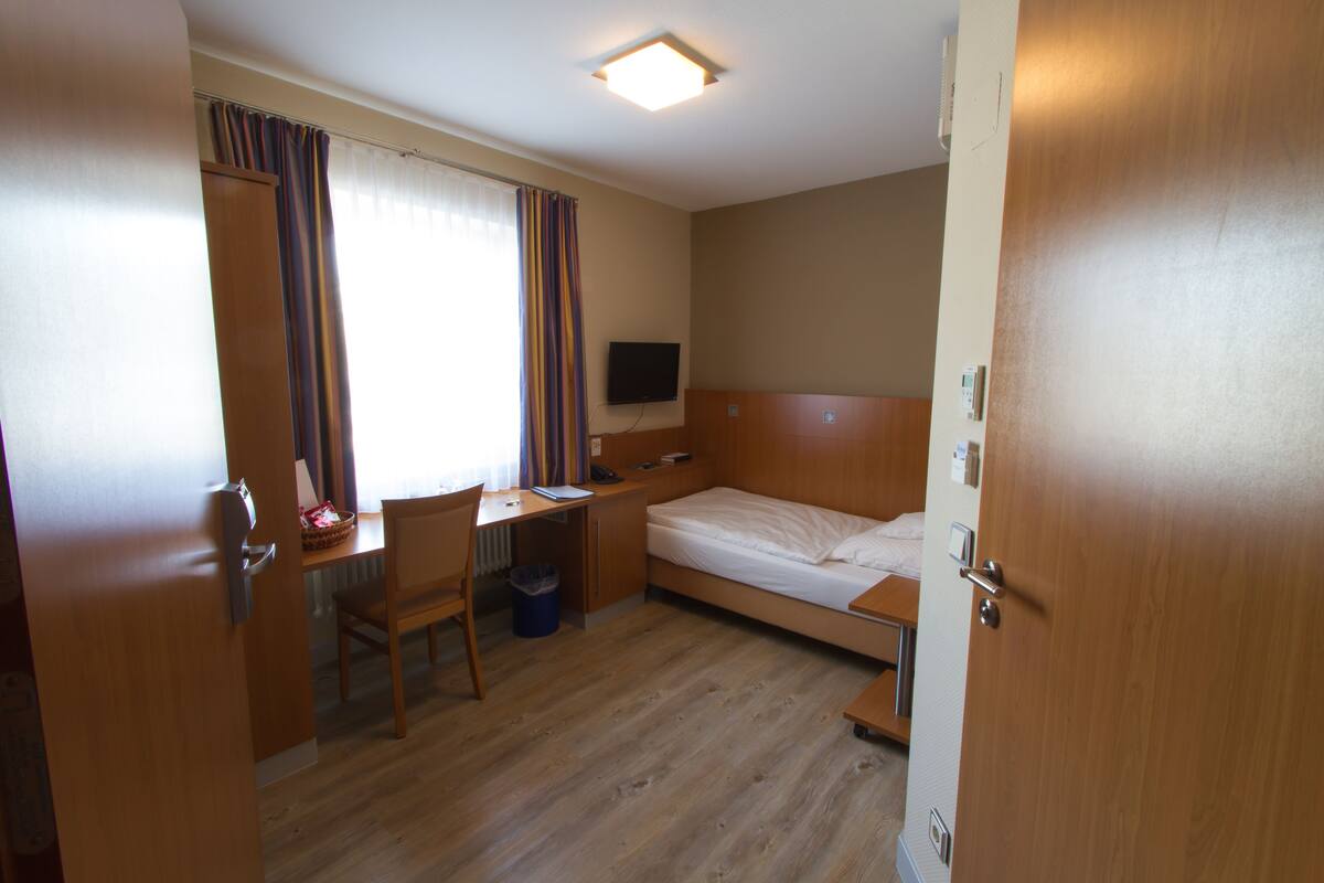 Een hotelkamer met een houten bureau, stoel en bed.