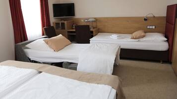 Habitación de hotel con dos camas, televisión, cabecera de madera, mesita de noche y lámpara.
