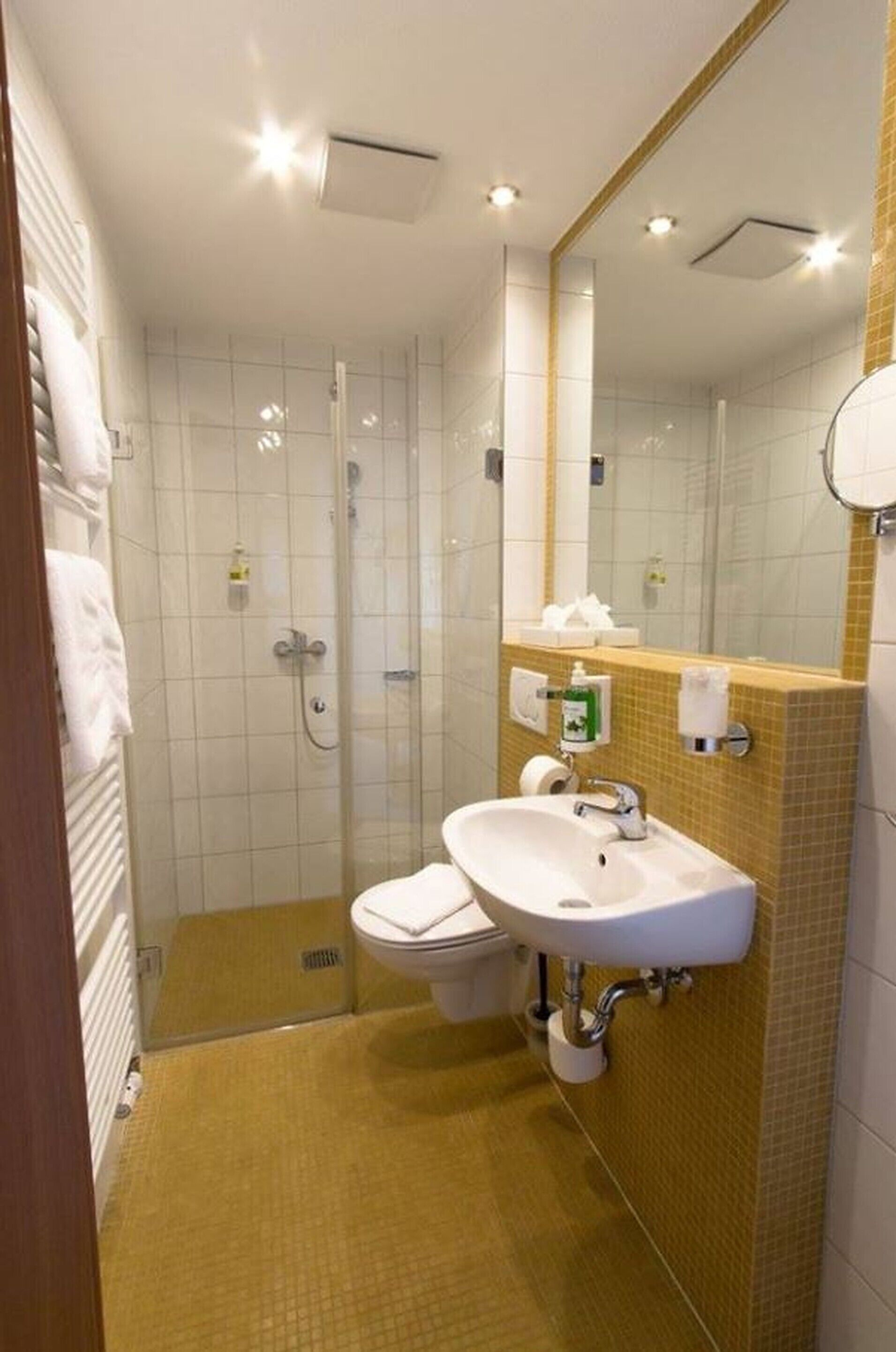 A bathroom with a shower, toilet, sink, and a mirror.