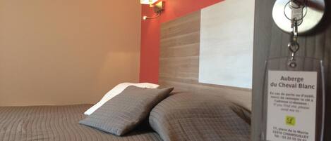 Una habitación de hotel con una cama, una lámpara de pared y un llavero con una etiqueta de nombre.