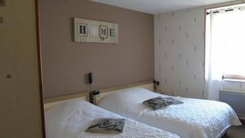 A hotel room with two beds, a wooden headboard, a wall-mounted phone, and a 'HOME' sign above the beds.