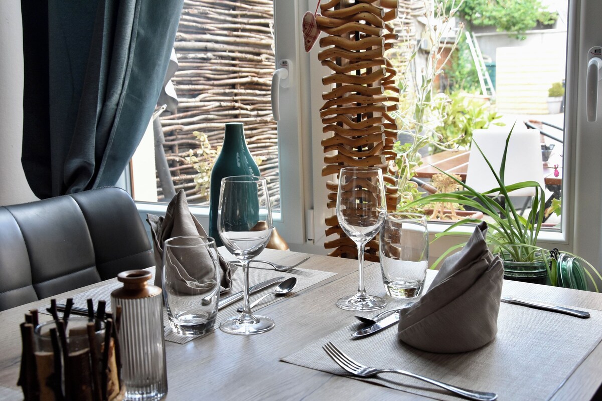 A dining table set with wine glasses, cutlery, and a vase.
