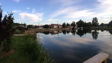 A calm river with a wooden dock and houses in the background.