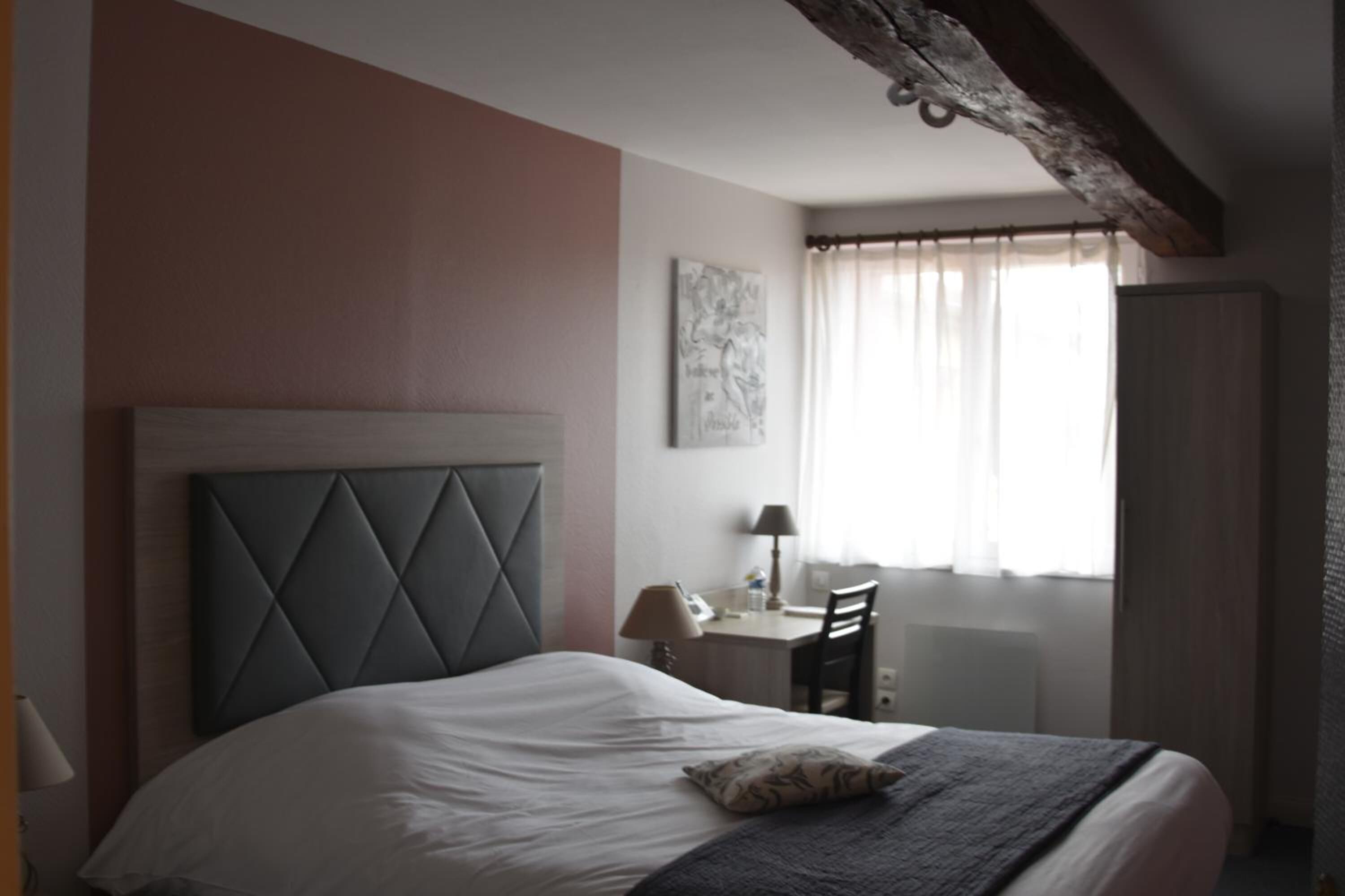 A hotel room with a large bed, a desk, and a chair.