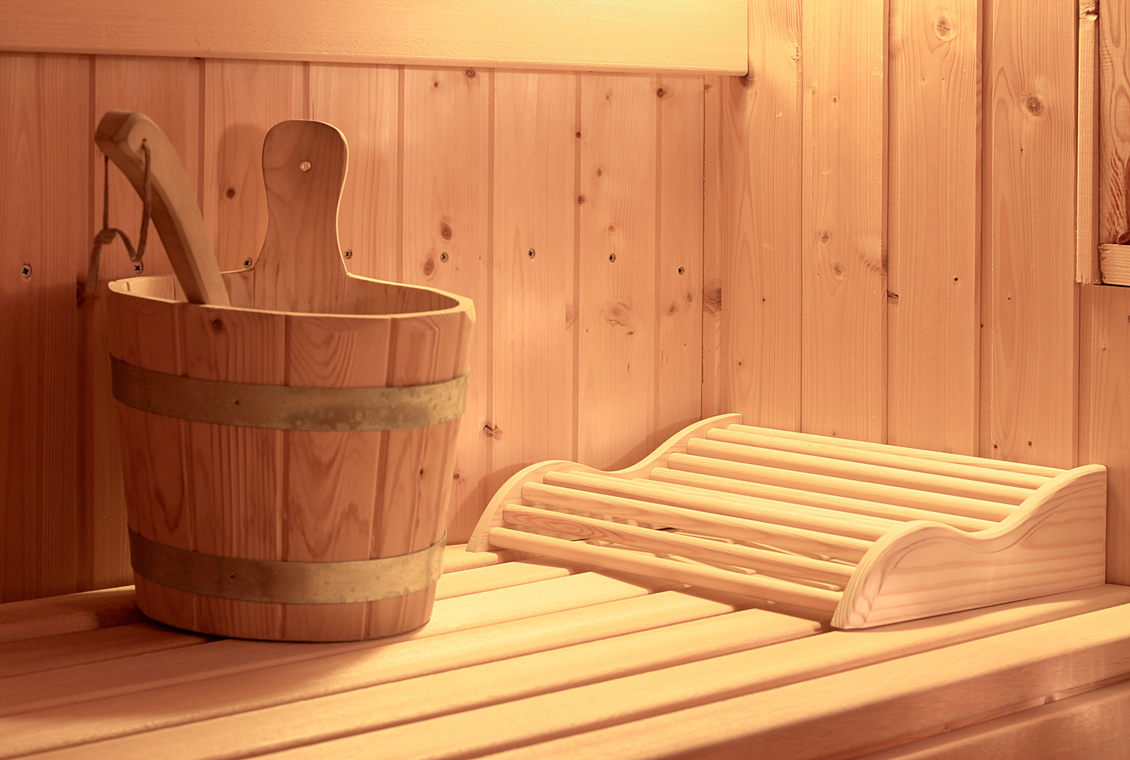 A wooden sauna bench and a wooden bucket with a ladle.