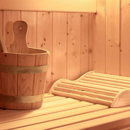 A wooden sauna bench and a wooden bucket with a ladle.