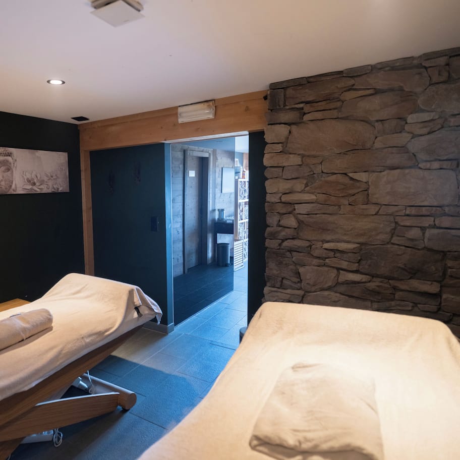 A room with two beds, a stone wall, and a Buddha statue on the wall.