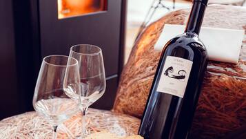 A cozy room with a fireplace, two wine glasses, a bottle of wine, and a plate of cookies on a woven stool.