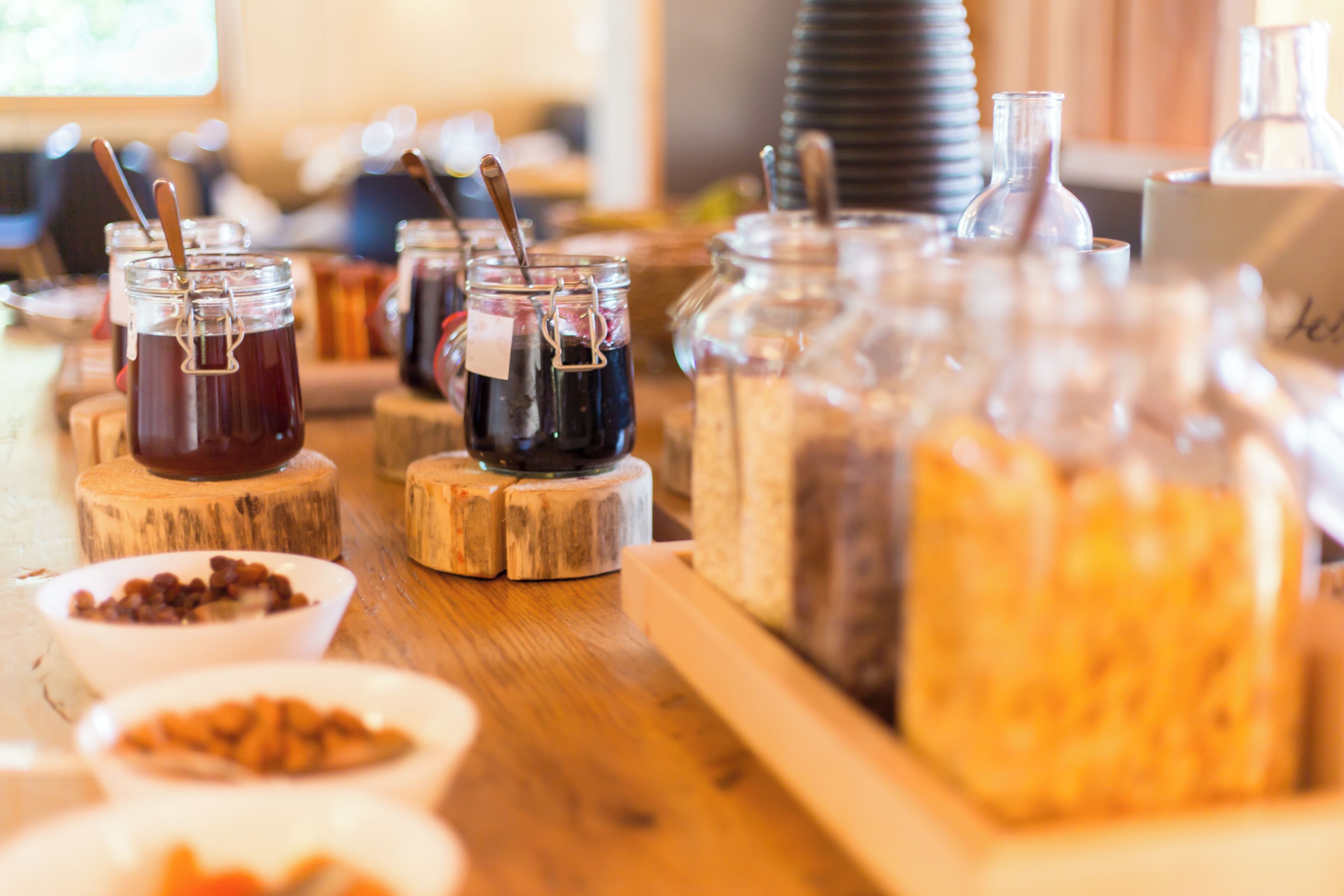 A buffet setup with various food items and beverages in glass containers on wooden stands.