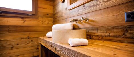 Baño de cabaña de madera con lavabo, espejo y ventana.