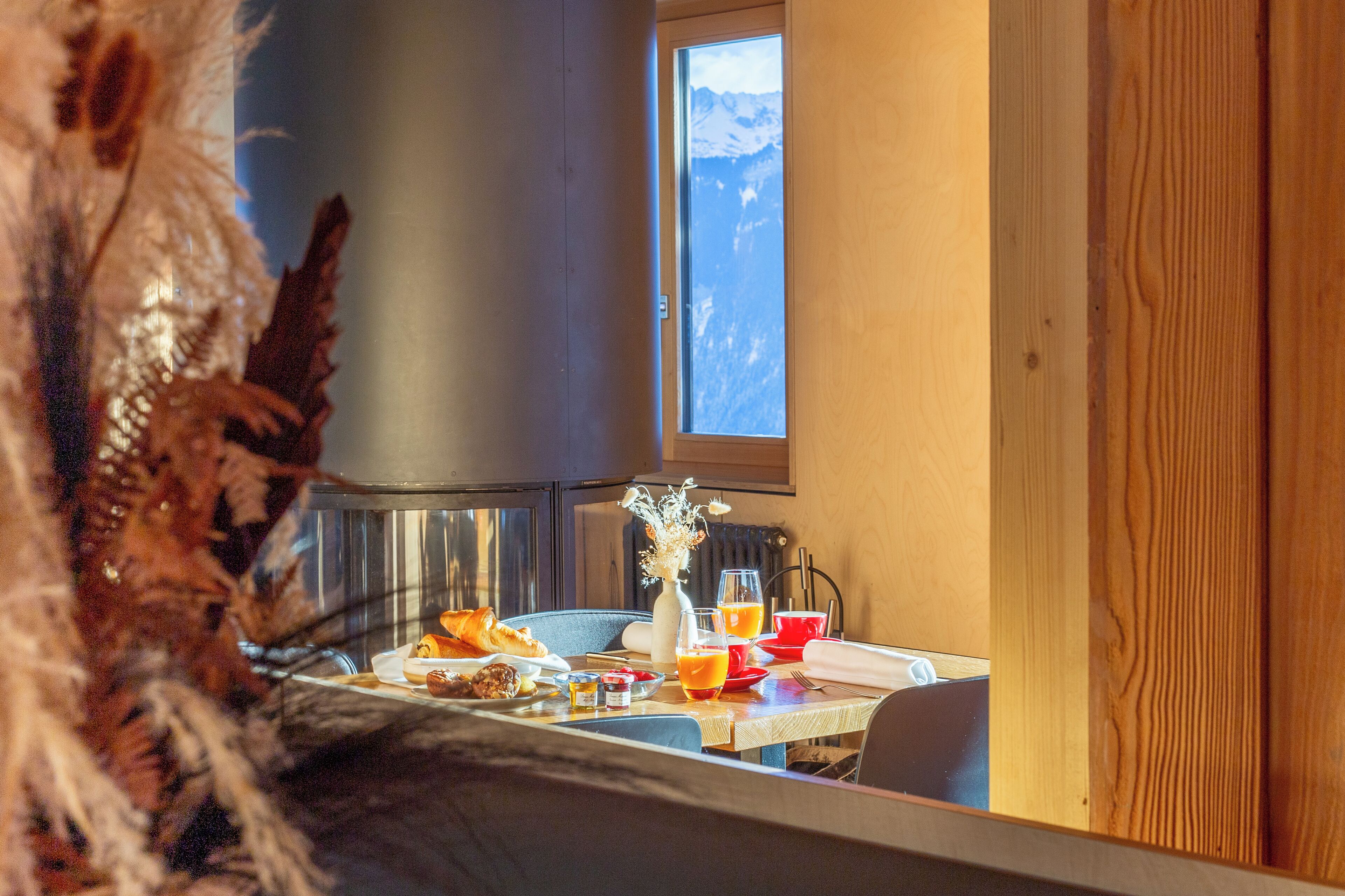 Une table de petit-déjeuner avec des croissants, du jus d’orange et un vase de fleurs.