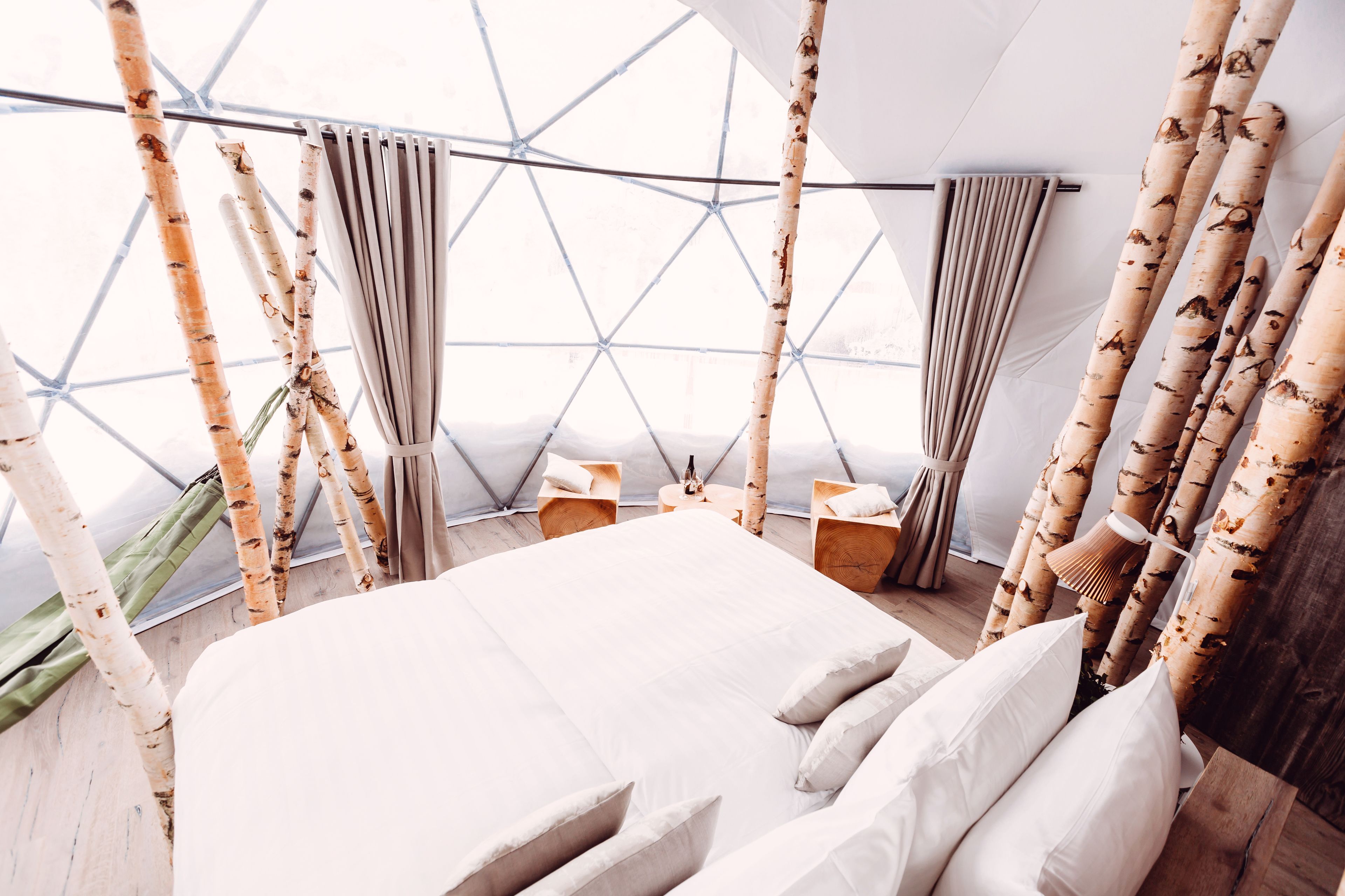 A modern, geometric-patterned room with a large bed, wooden furniture, and a unique geometric ceiling design.