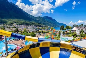 Un parc aquatique doté d’une grande piscine, de toboggans et offrant une vue sur une ville et des montagnes en arrière-plan.