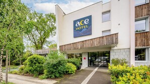L’extérieur de l’hôtel Ace, avec son entrée bien visible, une enseigne et la verdure qui l’entoure.