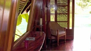 A wooden room with a bench, a chair, and a window with blinds. - Acajou Hotel (Grande Riviere)