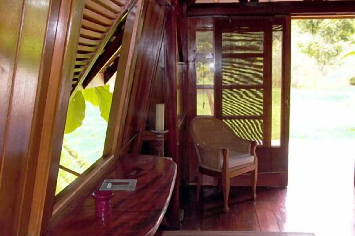 A wooden room with a bench, a chair, and a window with blinds.
