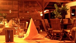 A dining area with wooden chairs and tables, a pyramid-shaped centerpiece, and candles. - Acajou Hotel (Grande Riviere)