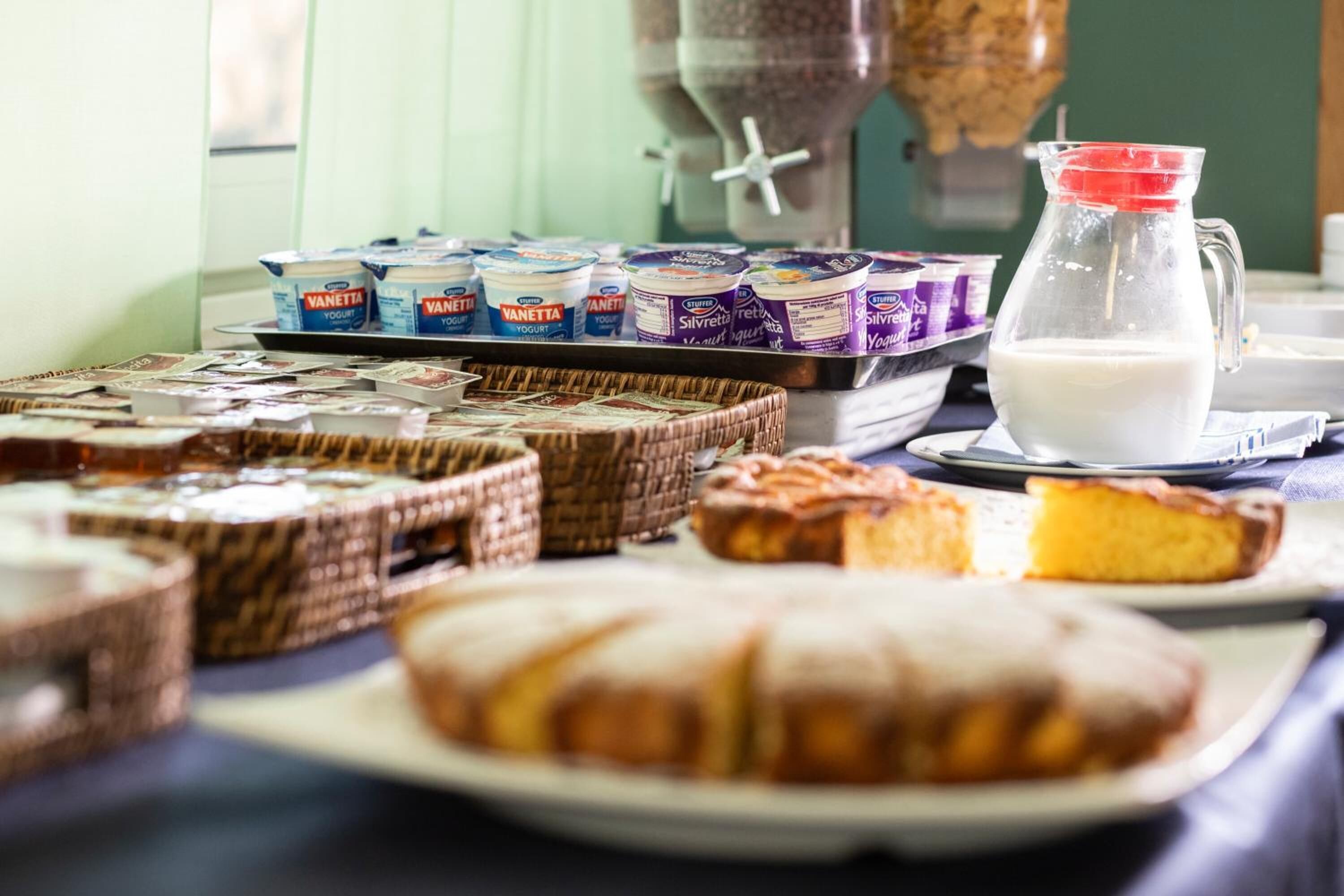 A breakfast buffet with various food items including pastries, cakes, and yogurt.