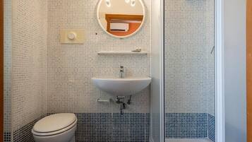 A bathroom with a toilet, sink, and shower.