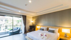 A modern hotel room with a large bed, two bedside lamps, a chair, and a balcony with a view of greenery.