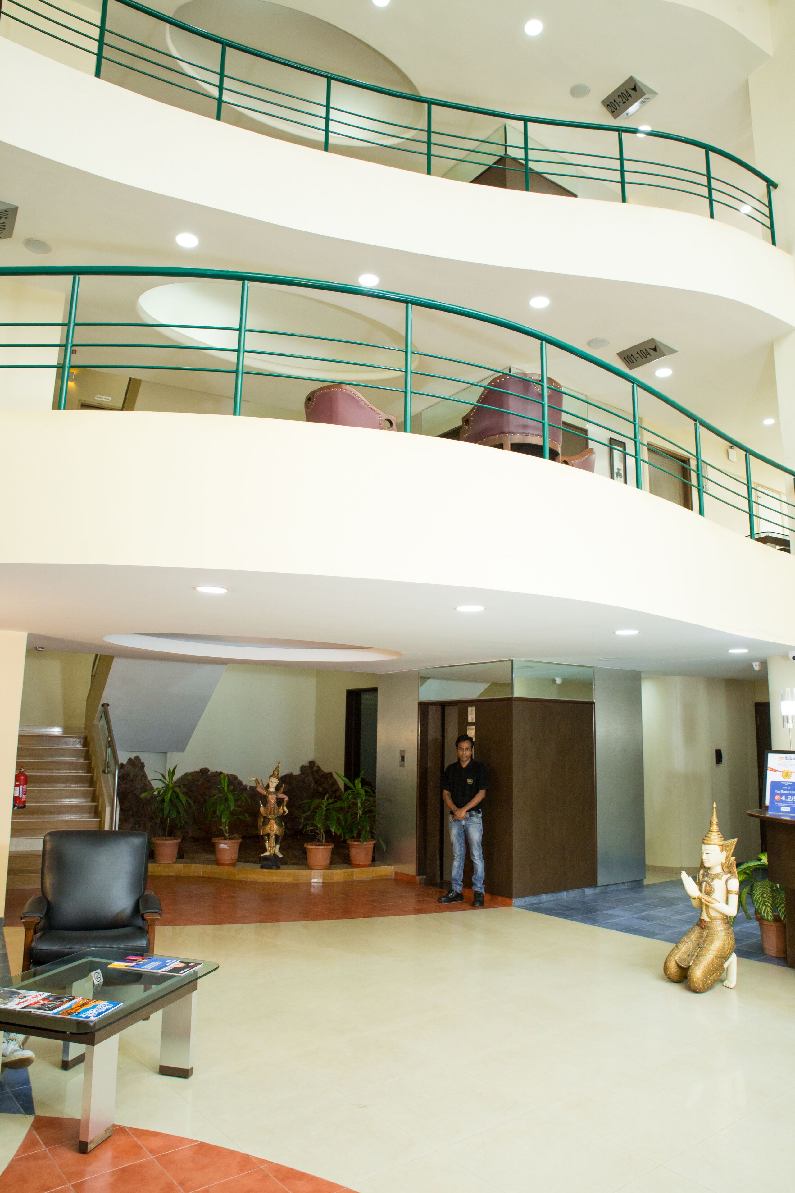 A multi-level lobby with a staircase, a reception desk, and a statue.