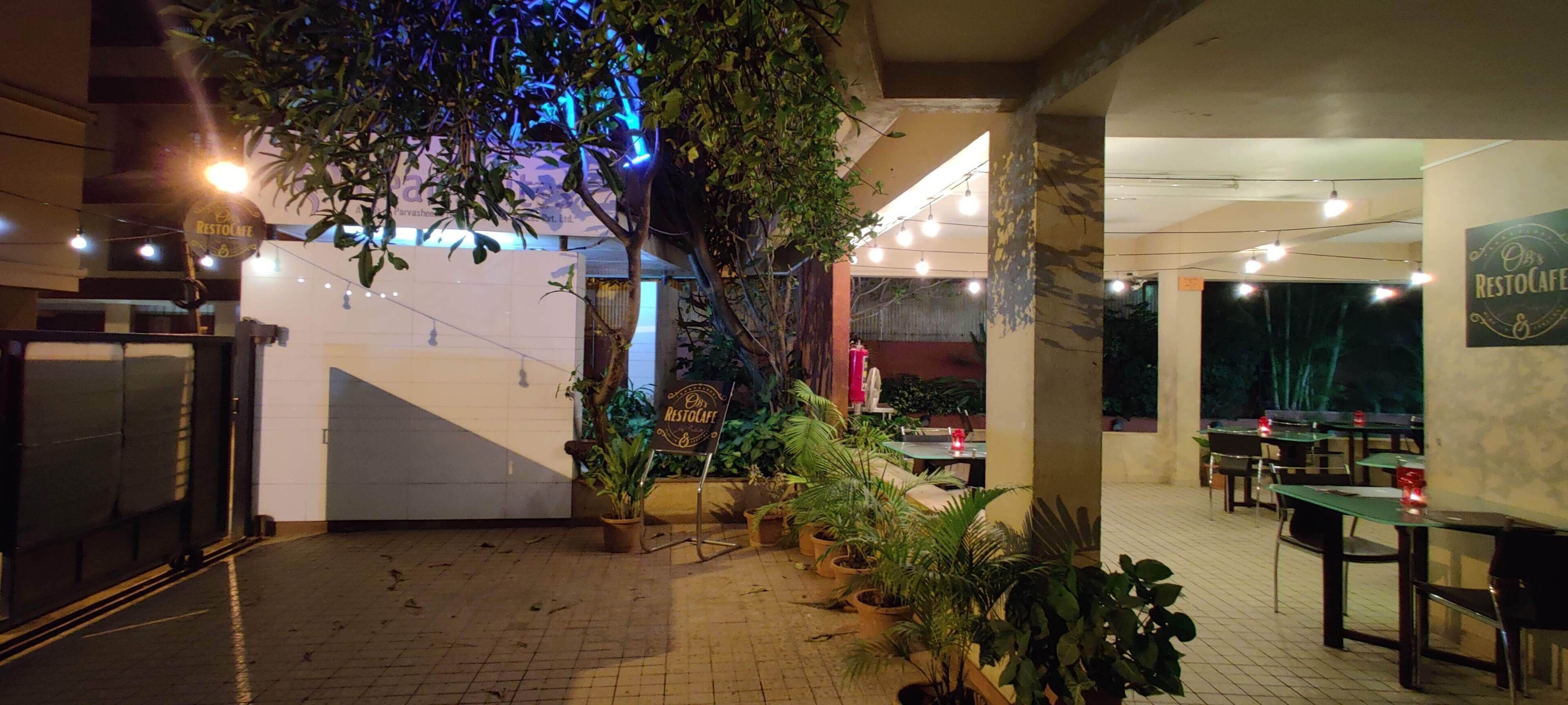 Restaurante interno com plantas em vasos, mesas e cadeiras.