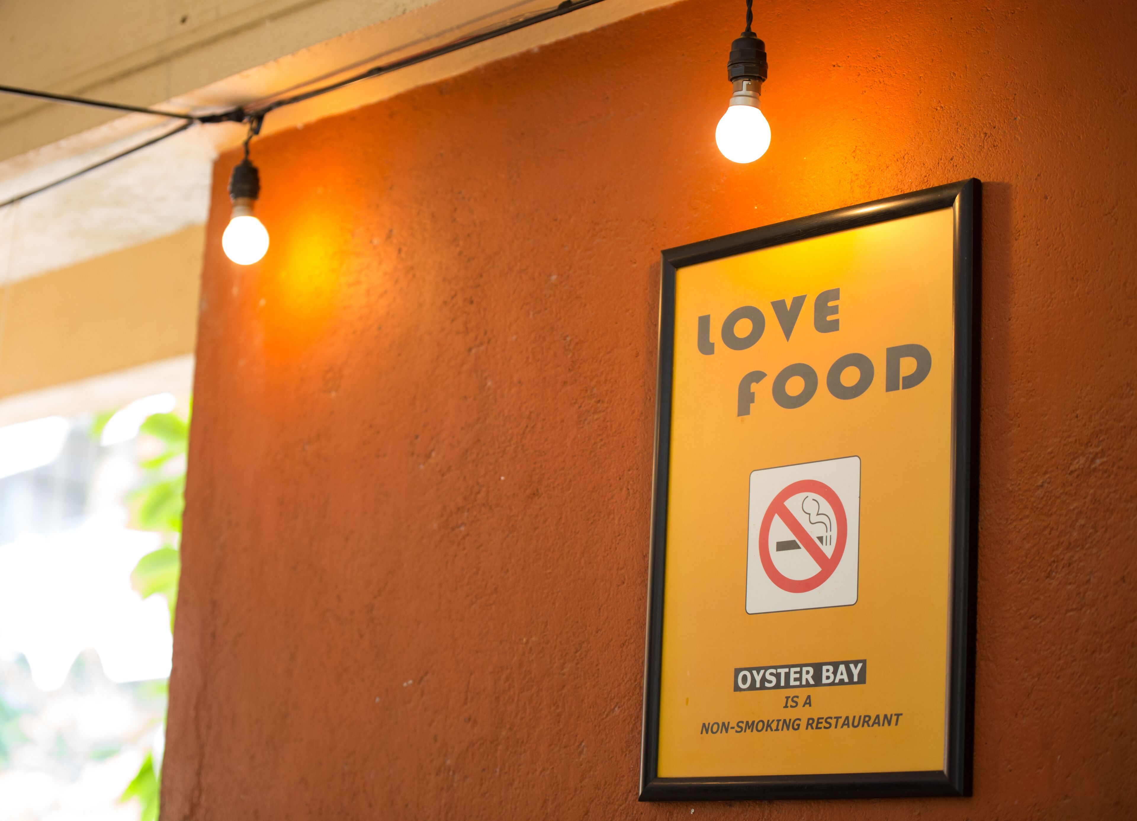 A framed sign with the text "LOVE FOOD" and a no-smoking symbol, indicating a non-smoking restaurant named Oyster Bay.