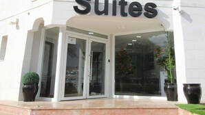 Hotellin sisäänkäynti, jossa on kyltti, jossa lukee ”Suites”, ja sen yläpuolella hotellin logo.