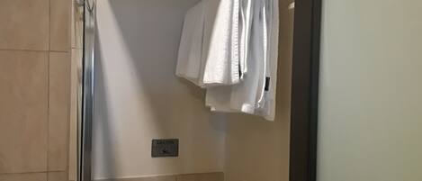 A bathroom with a shower, a towel rack, and a caution sign on the wall.