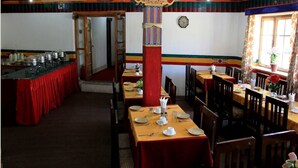 Un comedor con mesas dispuestas para comidas, un pilar decorativo y un reloj en la pared.