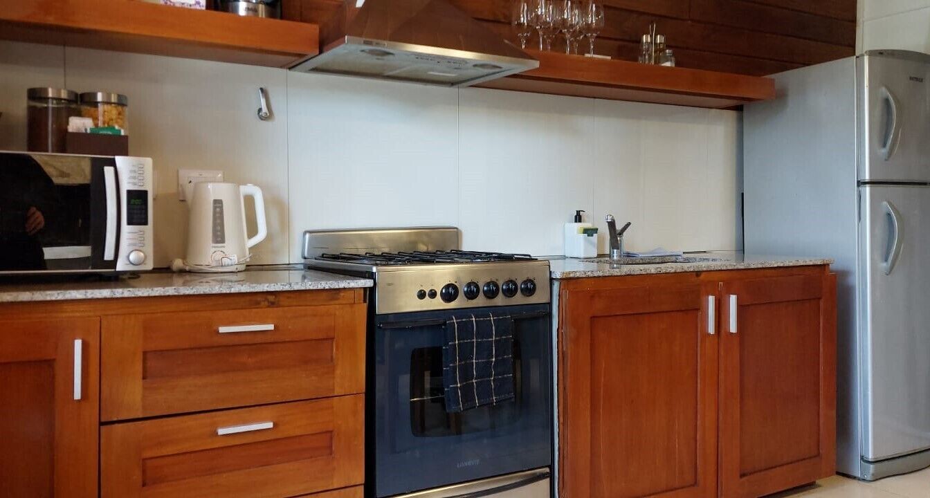 A kitchen with wooden cabinets, a stove, a microwave, and a refrigerator.