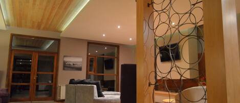 A spacious living area with a high ceiling, a large window, and a modern fireplace.