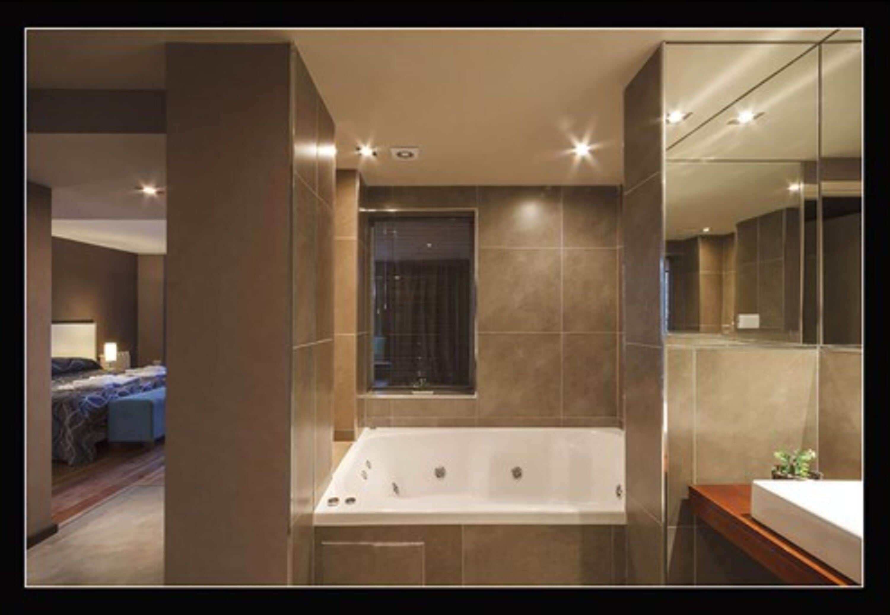 Une salle de bain moderne avec une grande baignoire, une fenêtre et un miroir.