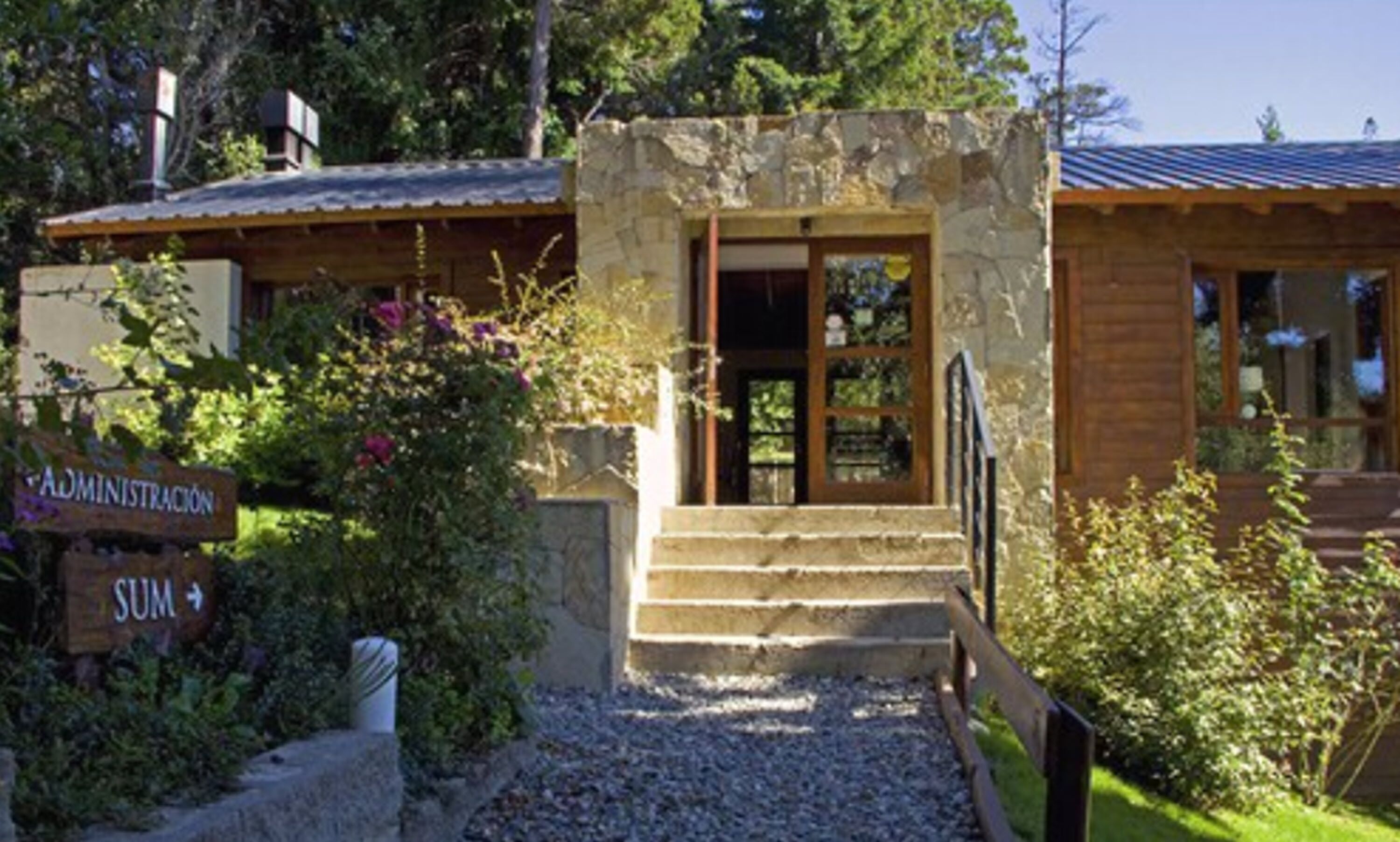 Un bâtiment en pierre avec une façade en bois, une enseigne indiquant « ADMINISTRATION », et un escalier menant à l’entrée.
