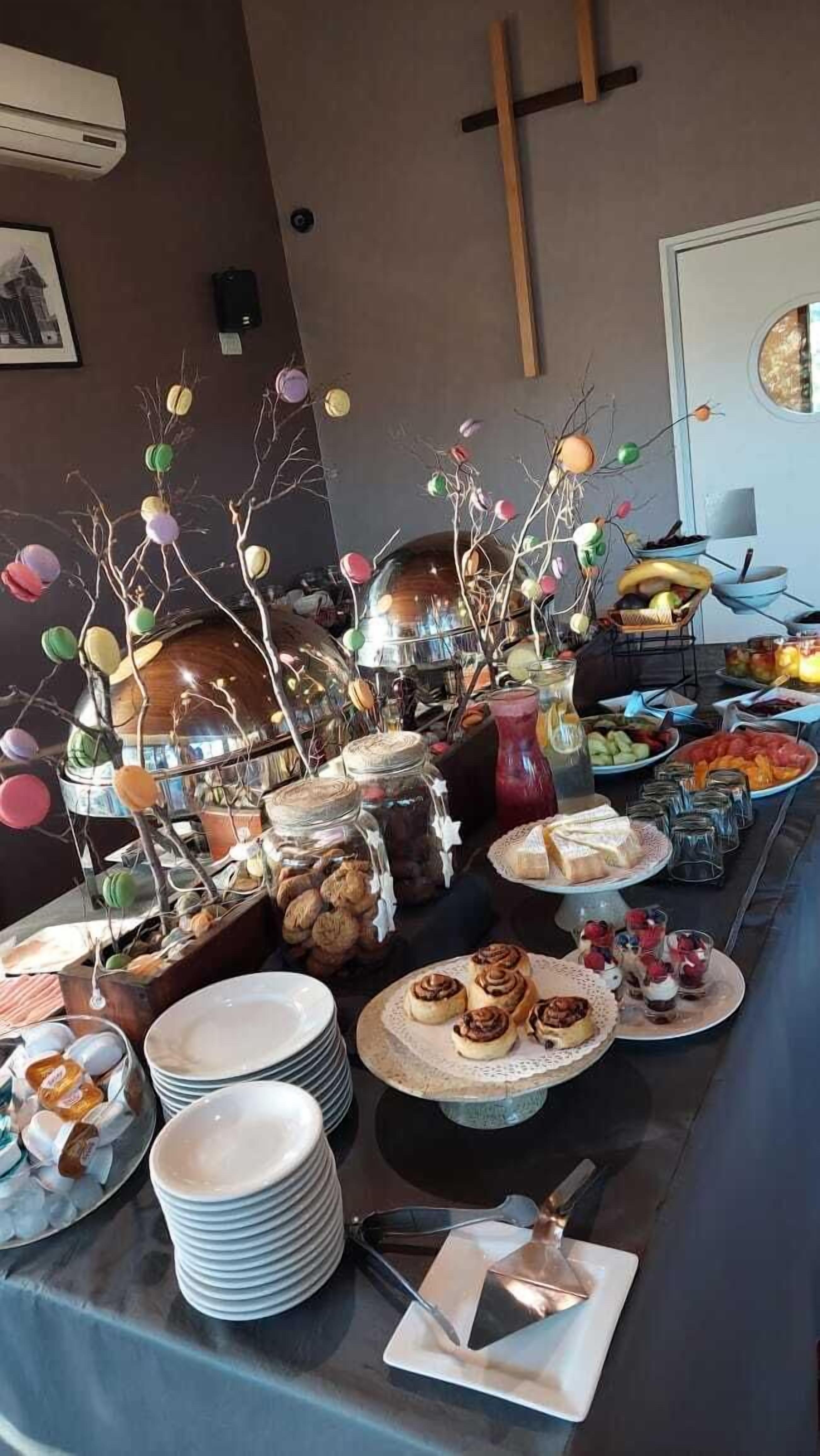 Une table de buffet proposant une variété d’aliments, notamment des pâtisseries, des fruits et des condiments.