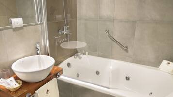 Une salle de bain moderne avec une grande baignoire blanche, un lavabo rond et une douche à parois de verre.