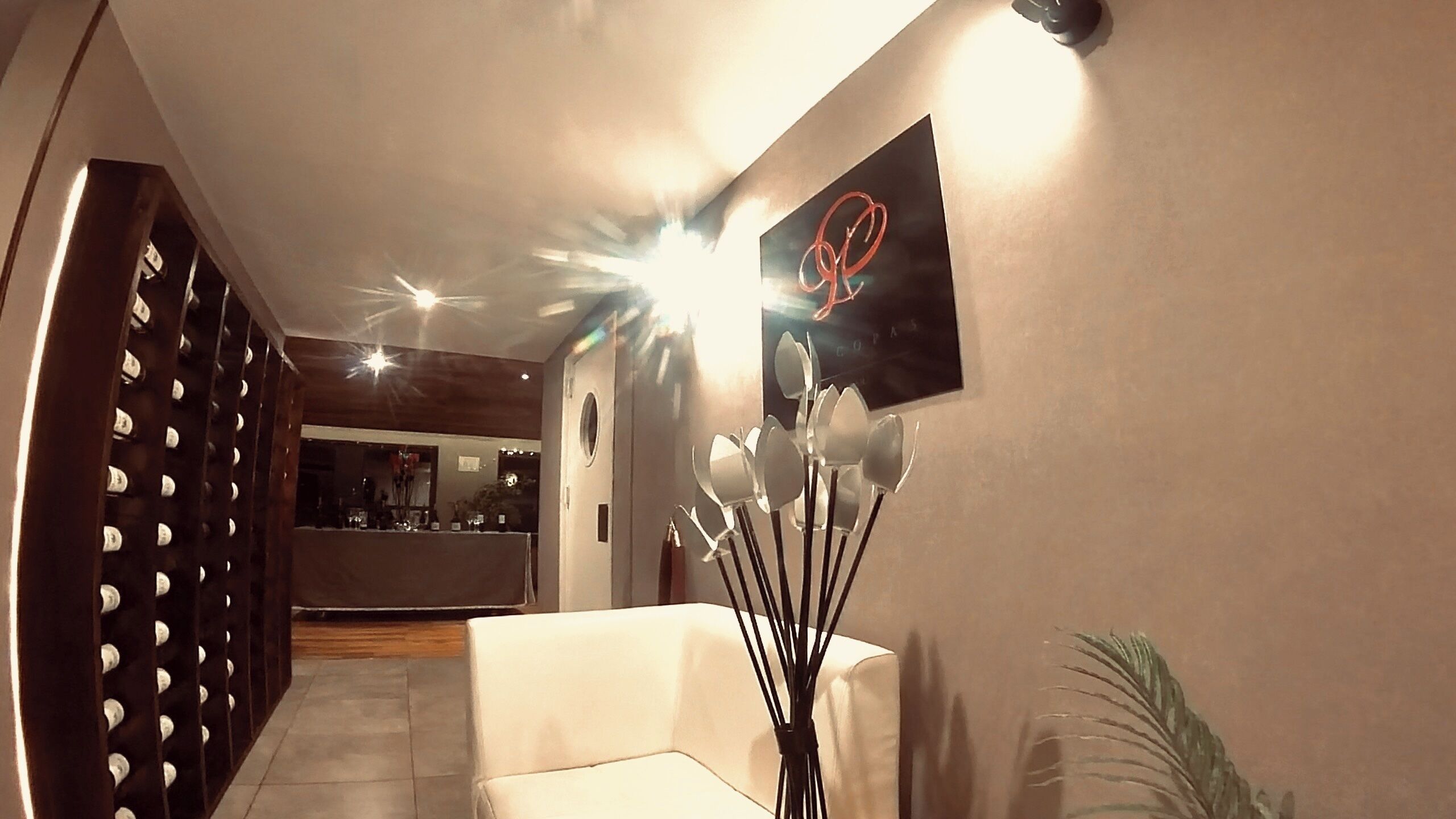 Un interior moderno con un sofá blanco, una obra de arte en la pared y un jarrón decorativo.