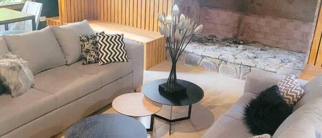 A modern living room with a sofa, two round tables, and a fireplace.