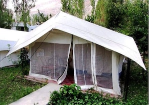 A tent with a peaked roof and a single entrance, surrounded by greenery. - TIH Mystique Meadows Camp (Leh)