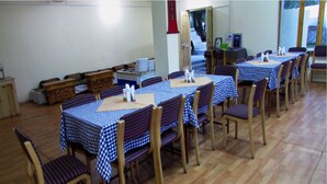 A dining area with multiple tables covered in checkered tablecloths, wooden chairs, and a wooden floor. - TIH Mystique Meadows Camp (Leh)