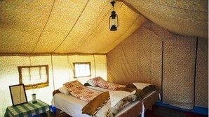 A tented room with two beds, a table, and a hanging light fixture. - TIH Mystique Meadows Camp (Leh)