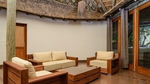 Ein modernes Wohnzimmer mit Holzmöbeln, einer Glastür zum Garten und einer Decke mit natürlicher Holzoptik.