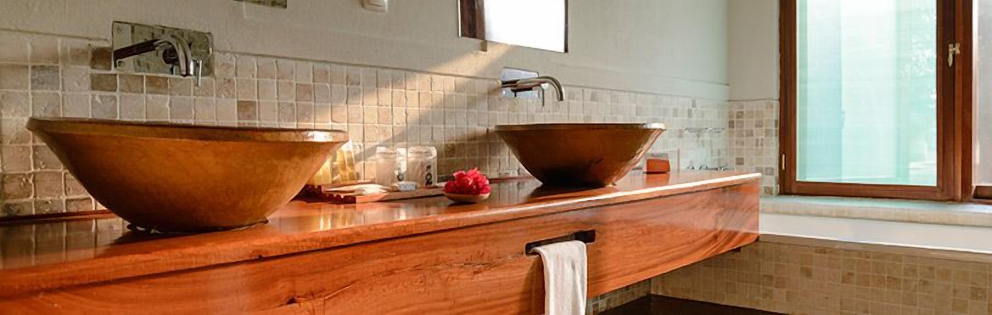 A bathroom with two large copper sinks, a wooden countertop, and a window providing natural light.