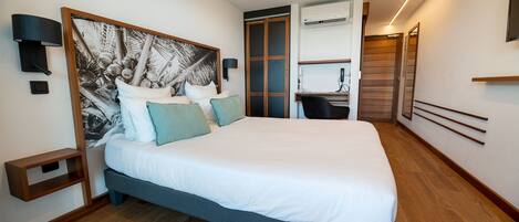 A modern hotel room with a large bed, a desk, and a wardrobe.