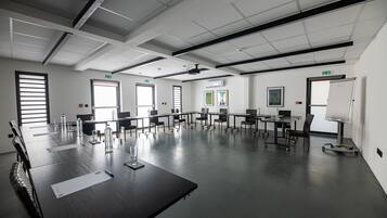 Un salón de conferencias con una larga mesa, sillas, una pizarra y un proyector.