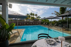 Una piscina al aire libre, sombrillas, sillones reclinables de piscina